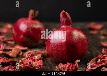 Zwei Granatäpfel auf einem schwarzen Tisch, süße rote Granatäpfel in der Küche Stockfoto