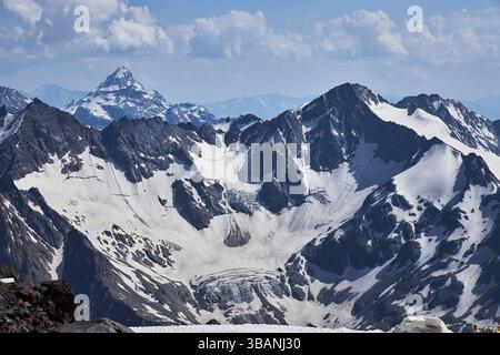 Schneebedeckte Bergketten erstrecken sich über die gesamte Landschaft mit zerklüfteten Gipfeln und einem riesigen Gletscher. Klarer blauer Himmel unterstreicht die Schönheit dieser Ruhe Stockfoto