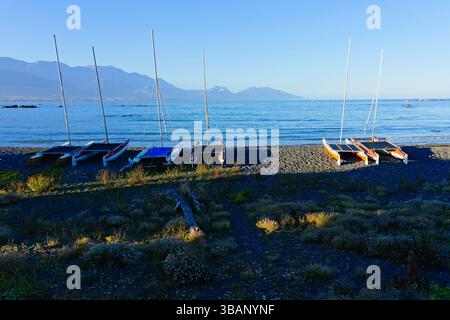 Fünf kleine Katamarane liefen am Strand von Kaikoura in der abendlichen Sommersonne. Stockfoto