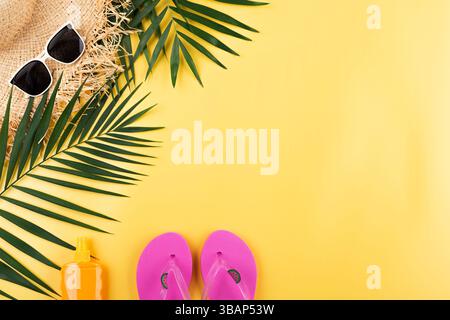 Urlaubsreiseplanung einfaches Thema der Strohhut Sonnenbrille Flipflops und Palmblätter auf einheitlichem gelbem Hintergrund flach mit Kopierraum Stockfoto