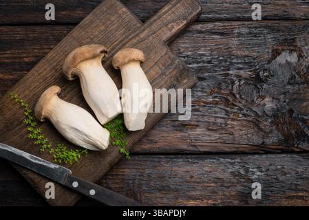 King Oyster Pilze bereit zum Kochen auf hölzernem Schneidebrett mit Messer, Kopierraum. Gesunde vegane vegetarische Lebensmittelzutat, Eryngii oder Trompetenbrei Stockfoto