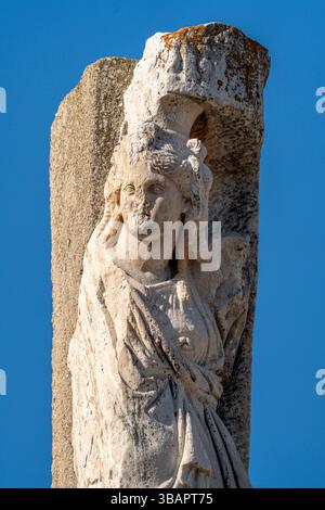 Statue aus dem Tempel des Domitians, ohne Kopf, in klassische Gewänder gehüllt, stehend gegen eine geschnitzte Steinsäule. Stockfoto