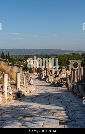 Curetes Street in Ephesus, die sich in Richtung Celsus Library erstreckt, ist mit Marmor gepflastert und mit gebrochenen Säulen und alten Fassaden gesäumt. Stockfoto