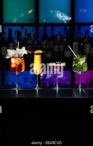 Reihe verschiedener farbenfroher alkoholischer Cocktails an einem Bartisch. Gläser unterschiedlicher Form Stockfoto