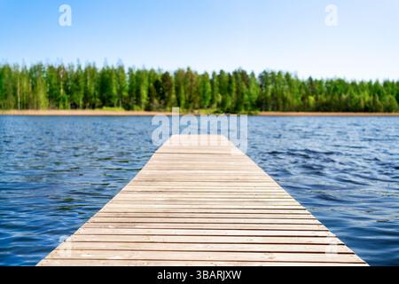 Dock und See Hintergrund. Finnland im Sommer. Wasser, Wald und Himmel. Holzpier im Fluss. Unscharfe Bäume. Blau und grün. Wunderschöne finnische Natur. Stockfoto