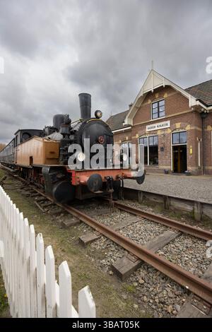Eine alte Dampfeisenbahn parkte auf Gleisen vor dem Bahnhofsgebäude in Friesland, Niederlande, die eine Nostalgie für eine vergangene Ära weckt Stockfoto