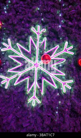 Große glühende Schneeflocke und rote Glaskugeln Nahaufnahme auf Weihnachtsbaum, helle und schöne Neujahrs- und Weihnachtsdekorationen, Feiertagshintergrund Stockfoto