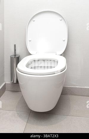 Saubere Toilettenschüssel mit offenem Deckel und Toilettenbürste in einem modernen Badezimmer Stockfoto