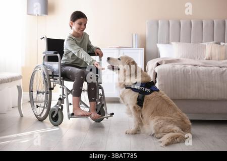 Mädchen im Rollstuhl mit ihrem Begleithund zu Hause Stockfoto