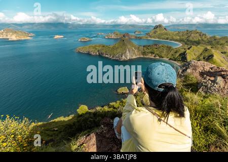 Junge Frau auf der Spitze des Aussichtspunkts Padar Island, die Fotos von der wunderschönen Landschaft Komod Labuan Bajo Indonesia macht Stockfoto