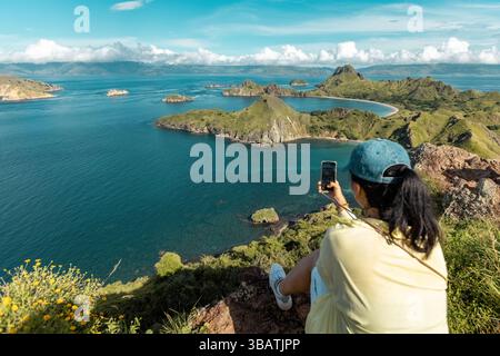 Junge Frau auf der Spitze des Aussichtspunkts Padar Island, die Fotos von der wunderschönen Landschaft Komod Labuan Bajo Indonesia macht Stockfoto