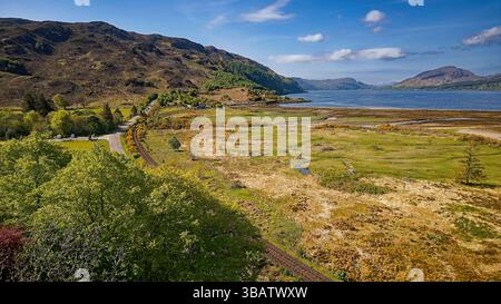 Lochcarron Wester Ross Scotland ein blauer Himmel im Frühling über dem Loch, der Eisenbahnlinie und der A890-Straße bei Attadale Stockfoto