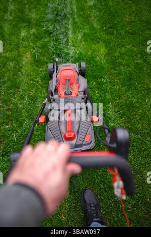 Genießen Sie einen perfekten Tag mit dem Rasenmähen an einem sonnigen Nachmittag in einem lebhaften grünen Garten Stockfoto