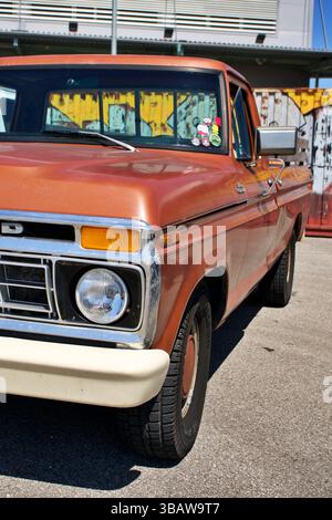 Vintage Rusty Orange Ford Pickup Truck parkt auf der Sunny Urban Street mit Aufklebern am Fenster Stockfoto