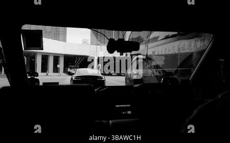 Hongkong - 3. Februar 2025 - durch das Fenster eines Uber, vor einem Tesla und Tourbus Zoll in Richtung eines Tunneleingangs. Stockfoto