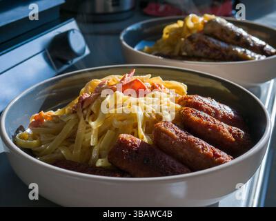Pasta mit knusprigen Speckwürsten, die in einer Keramikschale gedampft werden, was für einen reichen italienischen kulinarischen Komfort sorgt Stockfoto