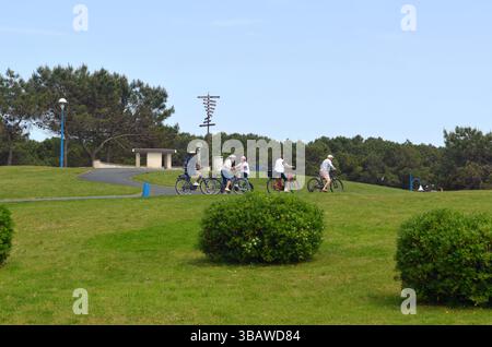 La Palmyre, Frankreich - 01. Mai 2025: Radfahrer fahren durch einen lebhaften Park mit Grün und Wegen, um Outdoor-Aktivitäten und soziale intera zu fördern Stockfoto