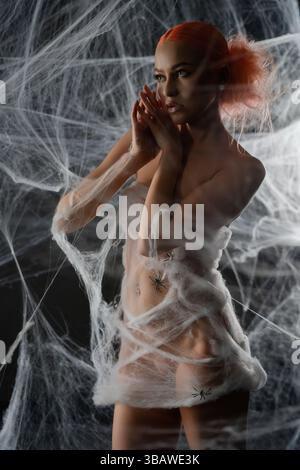 Rote Frau, die nachts in einer komplizierten Netzfalle gefangen ist, umgeben von Netzen Stockfoto