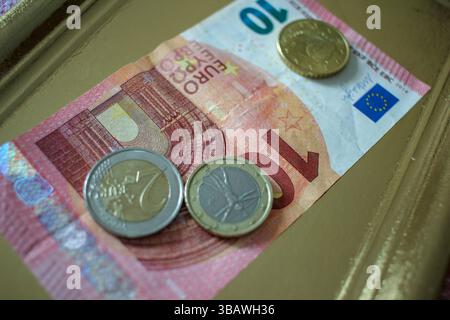 Euro-Münzen und eine zehn-Euro-Banknote auf einem goldenen Tablett Stockfoto