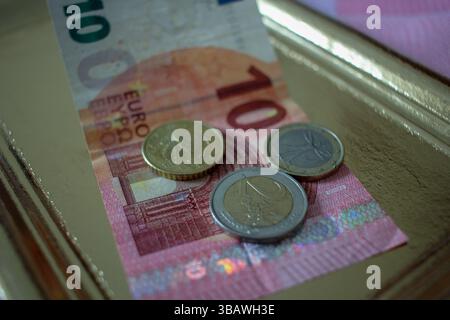 Euro-Münzen und Banknote auf einem goldenen Tablett Stockfoto