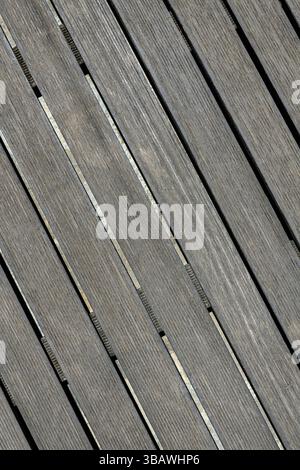 Nahaufnahme von altertümlichen grauen Holzdielen, die diagonal mit schmalen Spalten auf einem Betonsockel verlegt wurden. Sichtbare Holzstruktur. Ideal für Hintergründe Stockfoto