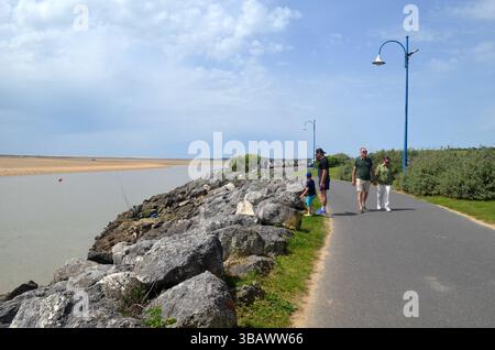 La Palmyre, Frankreich - 01. Mai 2025: Familie genießt einen gemütlichen Spaziergang entlang des malerischen Flusspfads mit felsiger Küste und üppigem Grün unter A Stockfoto