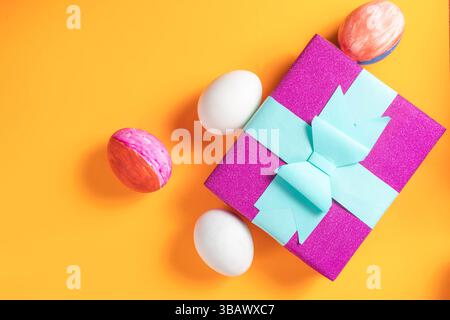 Die Osterschachtel und die dekorativen Eier auf einer orangen Oberfläche symbolisieren festliche Frühlingsfeste und fröhliche Feiertage. Stockfoto