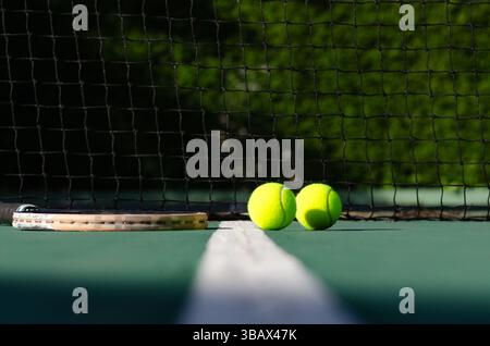 Ein Schläger und zwei Tennisbälle auf einem Tennisplatz. Stockfoto