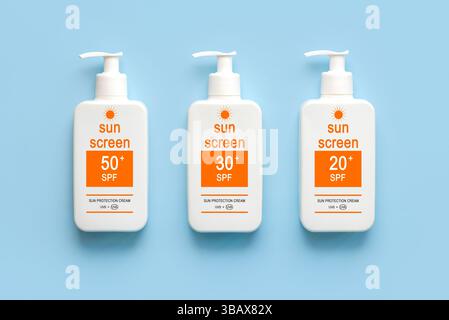Draufsicht von Flaschen mit Sonnencreme mit verschiedenen lsf-Nummern auf blauem Hintergrund. Konzept des Sonnenschutzes Stockfoto