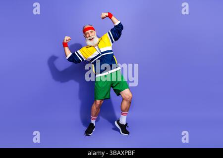 Ein älterer Mann mit sportlicher Vintage-Kleidung, der sich energetisch in einer selbstbewussten Pose beugt und Fitness und Begeisterung ausdrückt Stockfoto