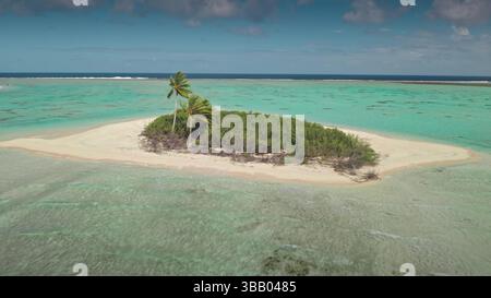 Aus der Vogelperspektive auf eine kleine einsame Insel mit Palmen und üppiger Vegetation, umgeben von einer türkisfarbenen Lagune und einem Korallenriff in Französisch-Polynesien, ein Traumziel für Urlaub und Entspannung Stockfoto