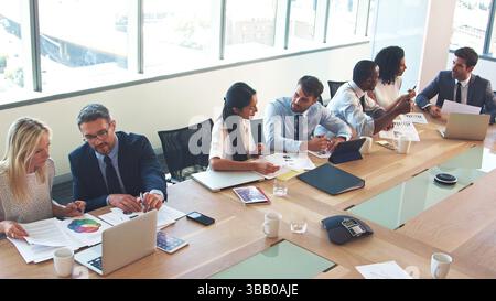 Hochwinkel-Ansicht Des Geschäftsteams Um Den Tisch In Modern Office, Das Zusammen Arbeitet Stockfoto