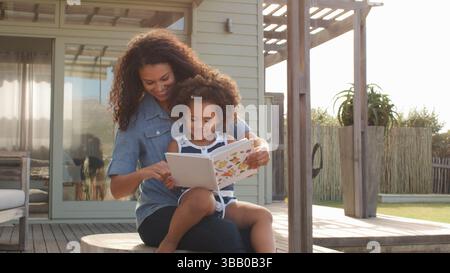 Mutter Sitzt Mit Tochter Draußen Und Liest Buch Zusammen Stockfoto
