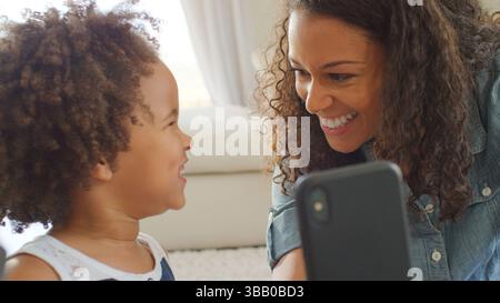 Mutter Sitzt Mit Tochter Zu Hause Und Nimmt Selfie Auf Dem Handy Stockfoto