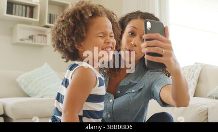 Mutter Sitzt Mit Tochter Zu Hause Und Nimmt Selfie Auf Dem Handy Stockfoto