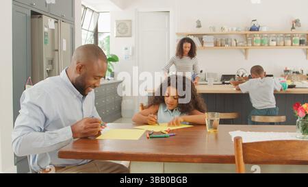 Familie Zu Hause In Der Küche Mit Vater Und Tochter, Die Zusammen Ein Bild Am Tisch Zeichnen Stockfoto