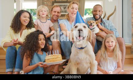 Familie Mit Freunden, Die Zu Hause Auf Dem Sofa Sitzen Und Geburtstag Mit Haustier Feiern Stockfoto