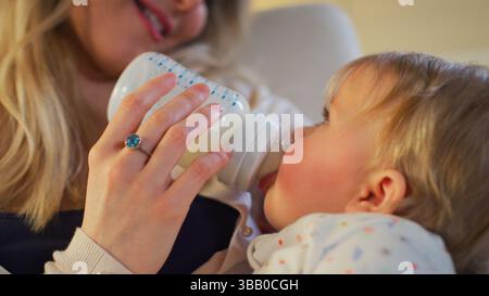 Nahaufnahme Der Mutter Im Kinderzimmer, Die Die Tochter Aus Bottle Füttert Stockfoto
