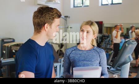 Mann, Der Im Fitnessstudio Trainieren Wird, Wird Von Weiblichen Personal Trainern Ermutigt Stockfoto