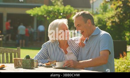 Seniorenpaar Genießt Tee Und Kuchen Rund Um Den Tisch Im Outdoor Café Stockfoto