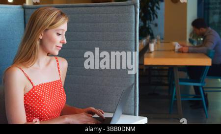Junge Geschäftsfrau Am Schreibtisch In Der Kabine Im Modernen Büroarbeitsplatz Mit Laptop Stockfoto