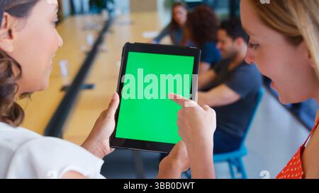 Nahaufnahme Von Zwei Geschäftsfrauen, Die Sich Ein Digitales Tablet Mit Grünem Bildschirm In Shared Office Ansehen Stockfoto