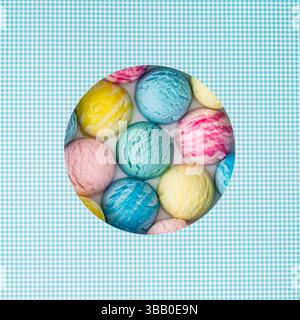 Kreative Sommerkomposition mit bunten Eiskugeln, sichtbar durch eine kreisförmige Lücke auf weißem und blauem Hintergrund. Süßes Food-Konzept. Stockfoto