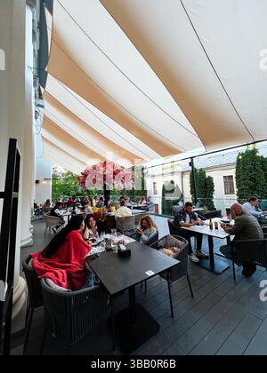 Iwano-Frankivsk, Ukraine - 14. Mai 2025: Gäste, die auf einer Terrasse mit Leinwänden und einer dekorierten Umgebung speisen. Stockfoto
