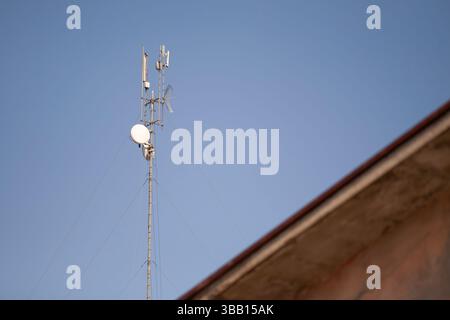 Telekommunikationsturm mit verschiedenen Antennen und Schalen, hoch vor einem klaren blauen Himmel, symbolisiert Konnektivität und Netzwerkinfrastruktur Stockfoto