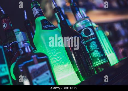 Rom, italien 4. Mai 2025: Verschiedene Spirituosenflaschen leuchten auf einem Regal in einer Bar und schaffen eine lebendige und farbenfrohe Atmosphäre Stockfoto