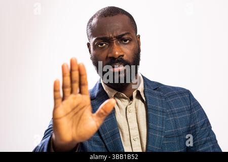 Porträt eines ernsthaften und nachdenklichen Geschäftsmannes. Schwarzer Mann im Business-Anzug zeigt Stop-Geste mit der Hand. Stockfoto