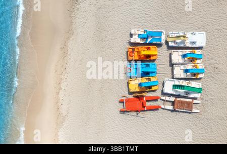Blick aus der Vogelperspektive auf farbenfrohe Katamarane am Sandstrand und dem blauen Meer Stockfoto