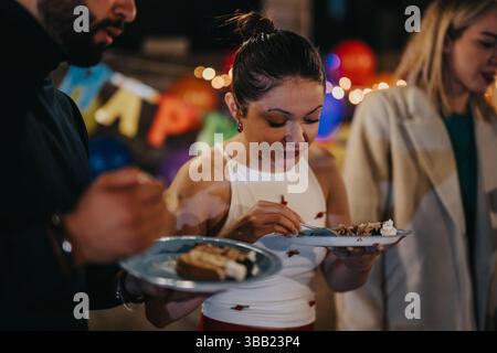 Freunde teilen sich Kuchen während einer festlichen Geburtstagsfeier im Hinterhof Stockfoto