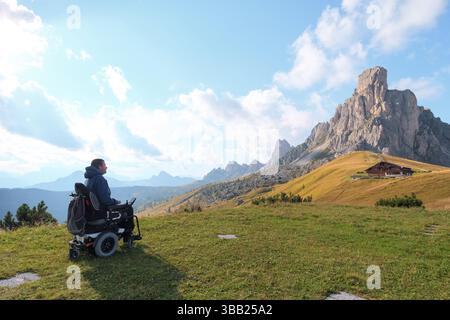 Behinderte Menschen im Rollstuhl bewundern die atemberaubende Landschaft der Dolomiten, Italien. Umgeben von majestätischen Bergen am Giau Pass. Stockfoto
